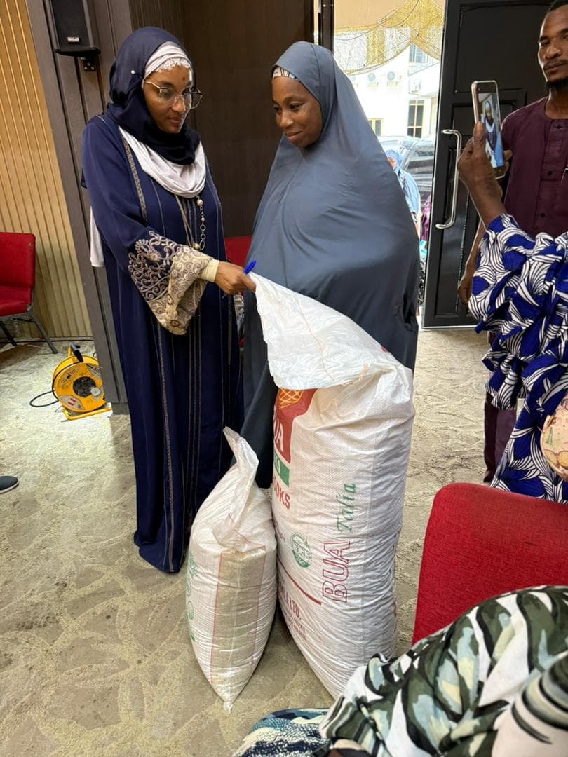 A Maidabo Foundation representative with a woman receiving food aid sacks during a distribution event